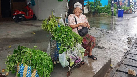 เอ็นดู "คุณยายยอดขยัน" ใช้ถุงคลุมหัวนั่งขายผักกลางสายฝน ยกมือไหว้วอนคนช่วยซื้อ